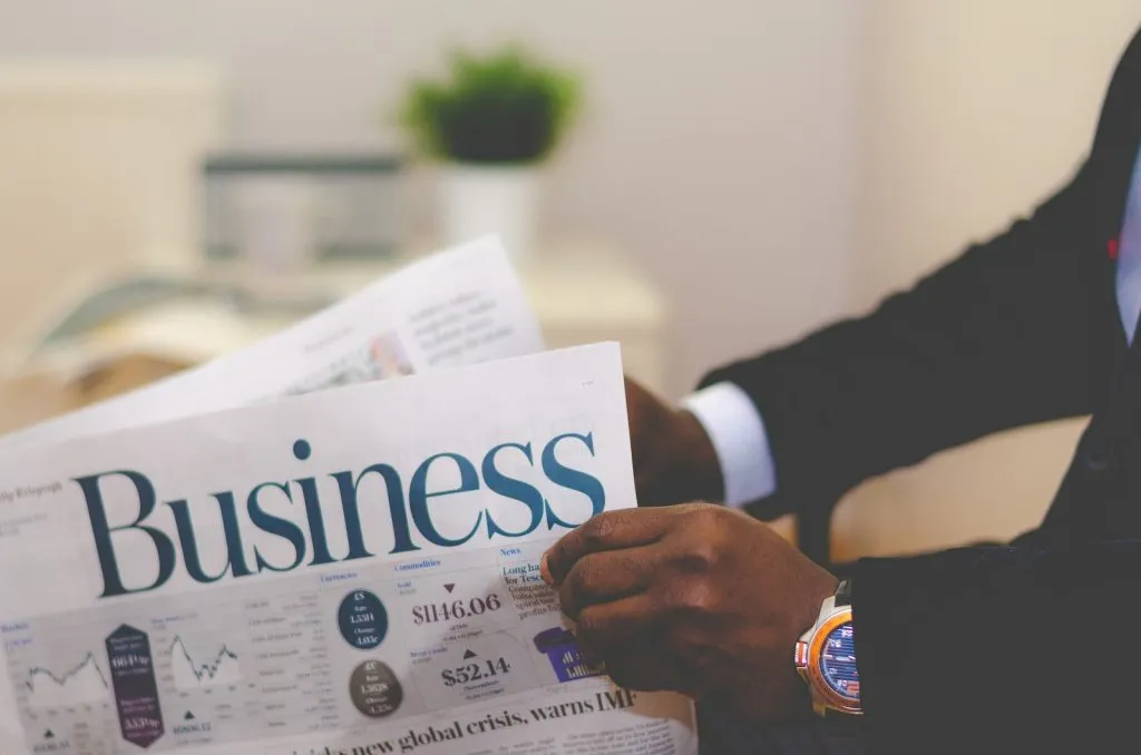 person wearing suit reading business newspaper, Advertising, tender notice, Tendering Process In Construction
