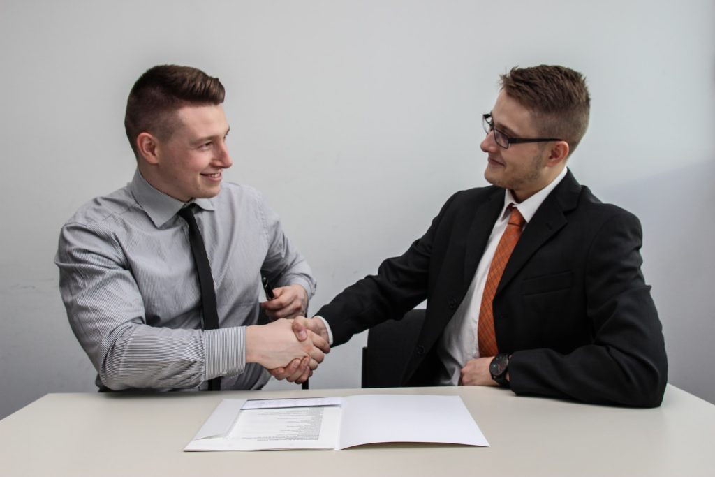two men facing each other while shake hands and smiling, Verbal contracts, verbal agreement , Written agreement