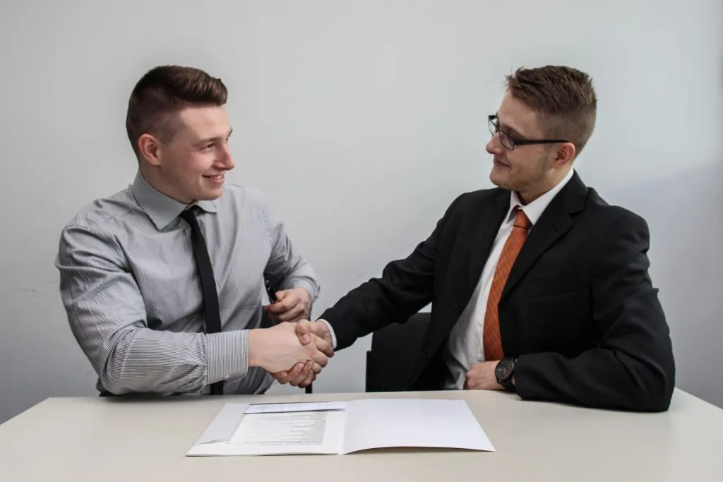 two men facing each other while shake hands and smiling, Verbal contracts, verbal agreement , Written agreement