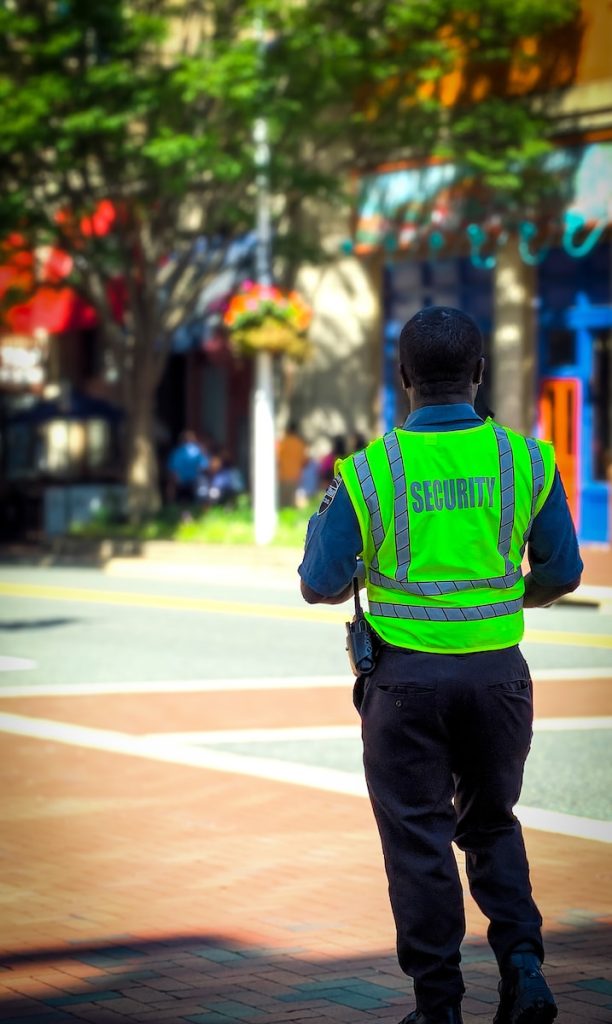 man in green and blue jacket walking on street during daytime , Security Guards construction